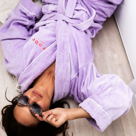 lady laying on floor in purple bathrobe wearing sunglasses - Robe Society